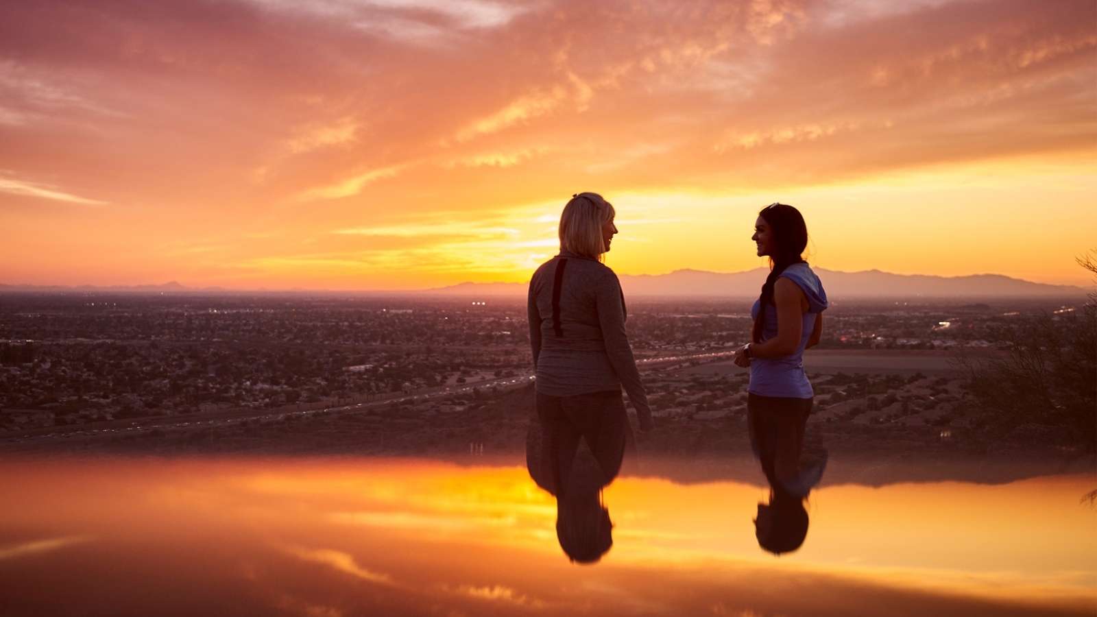 2 people smiling in front of a sunset