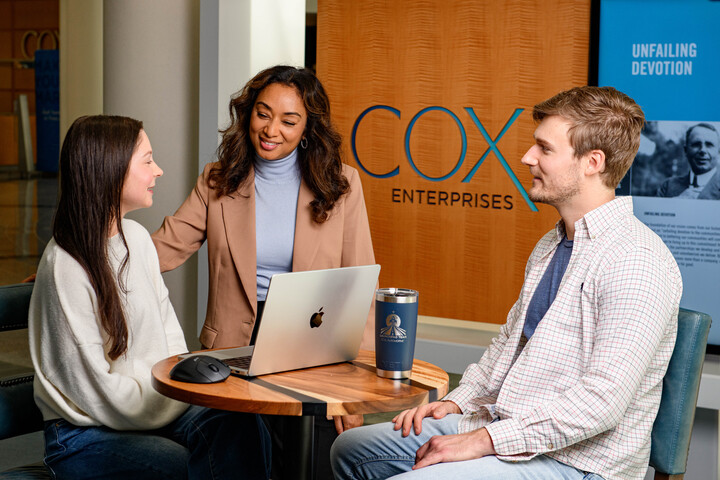 a group of Cox employees sitting at a table with a laptop
