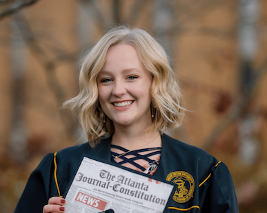 An AJC employee holding up her graduation cap