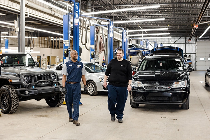 two Cox auto techs walking inside a body shop