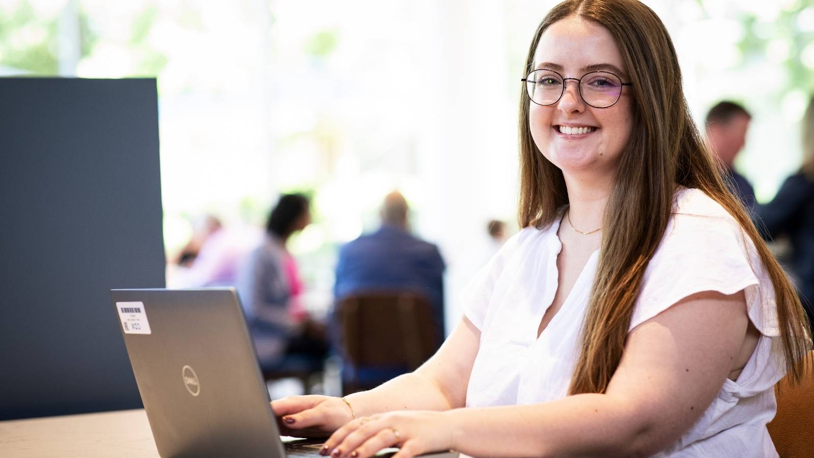 a Cox employee sitting with a laptop and smiling at the camera