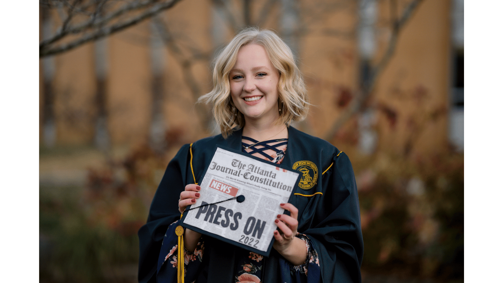 a person in a graduation gown holding a sign
