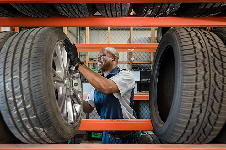 a Cox auto tech grabbing a large spare tire