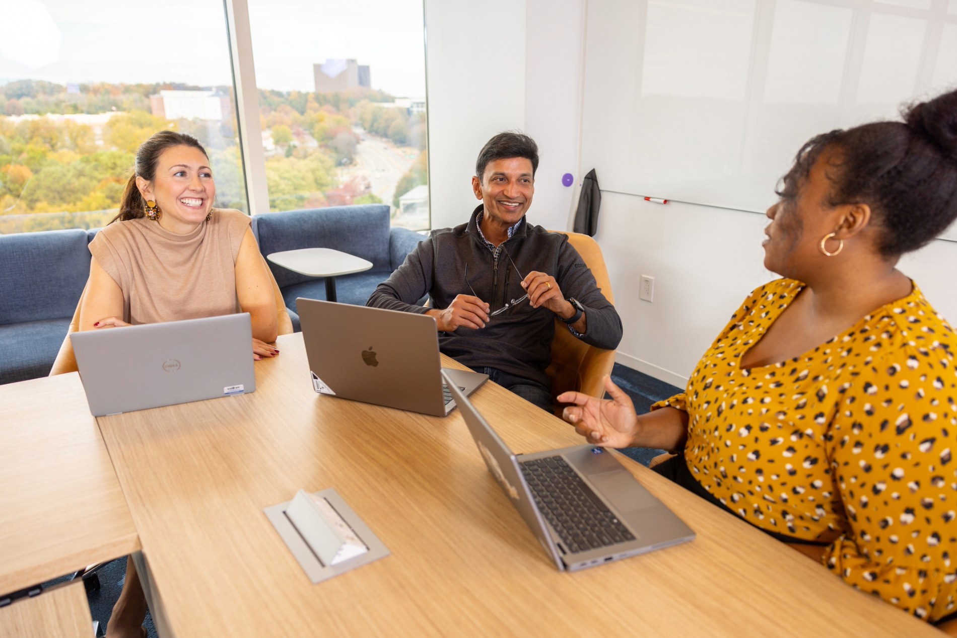 a group of people sitting around a table with laptops