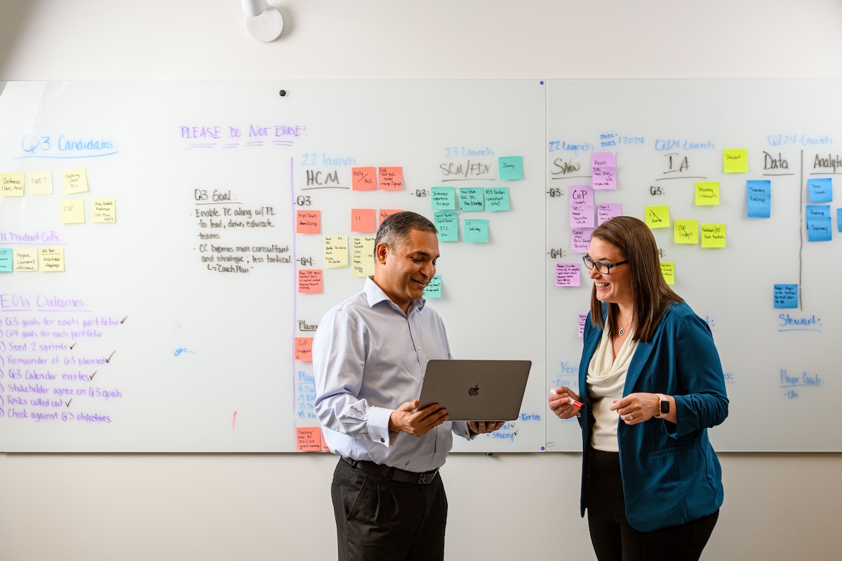 a person and person standing in front of a whiteboard with post-it notes