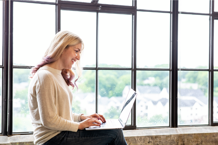 Cox employee working on laptop in front of window