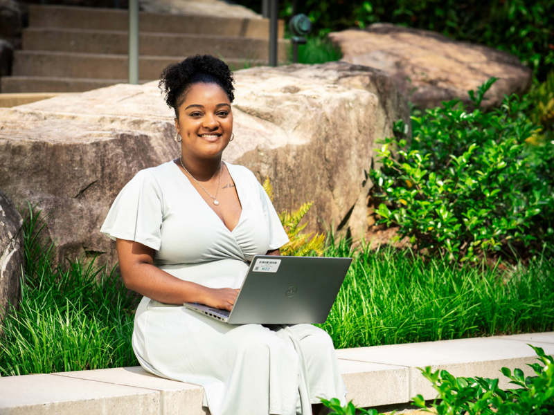 a person sitting on a ledge with a laptop